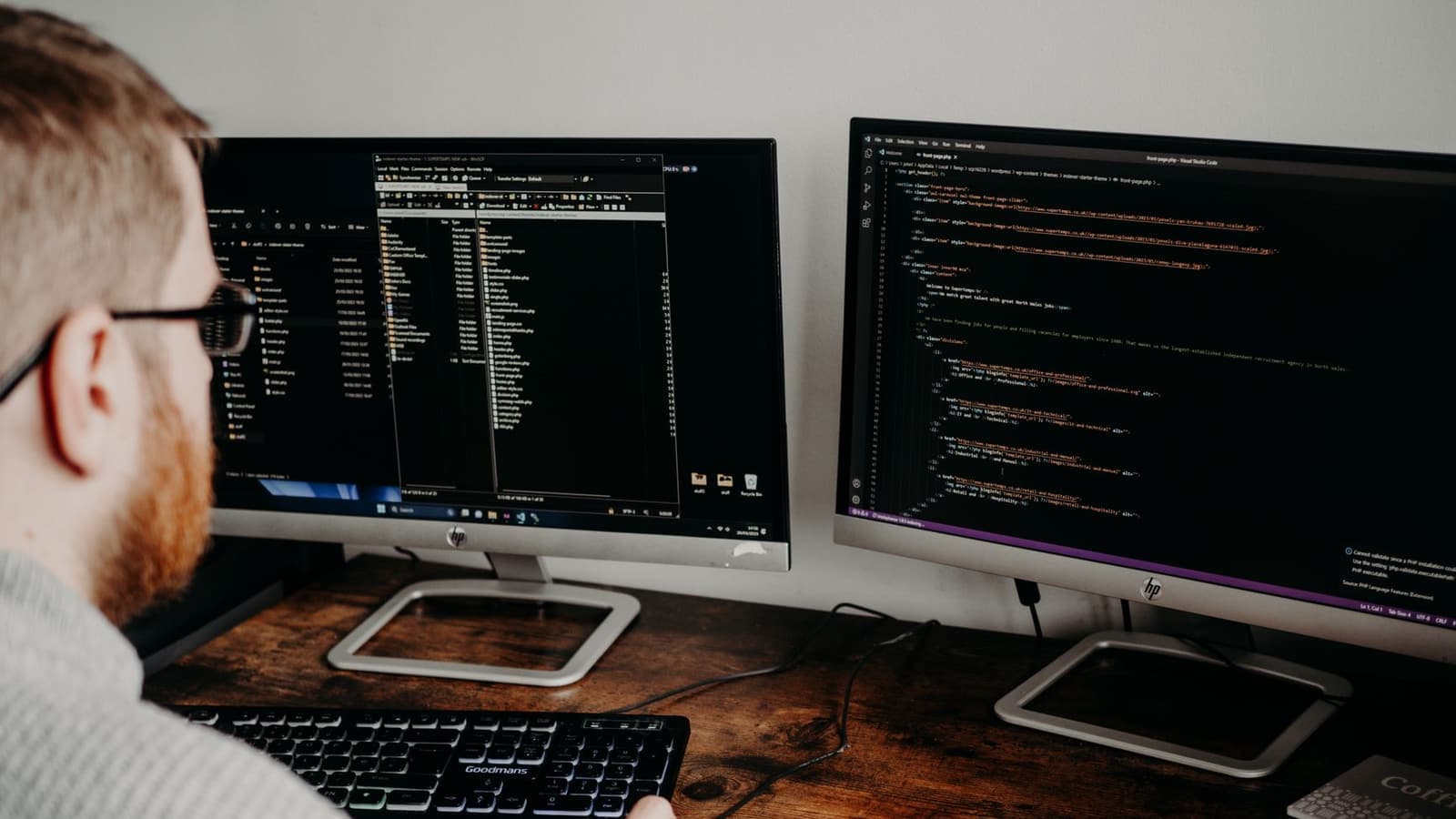 A developer reviewing website code across two monitors.