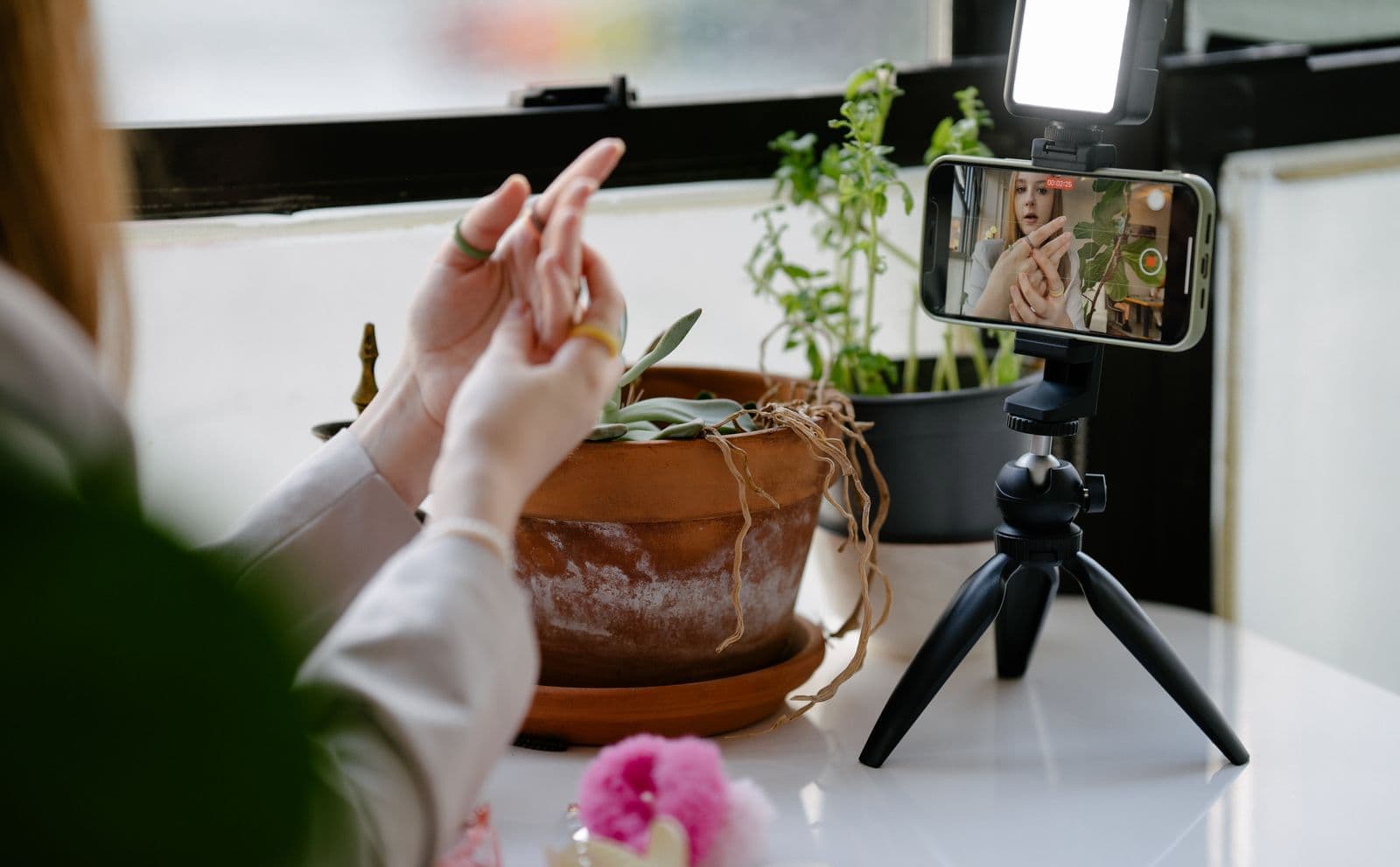 Content creator filming a video with a smartphone mounted on a tripod with a ring light, framing a multi-format piece of content